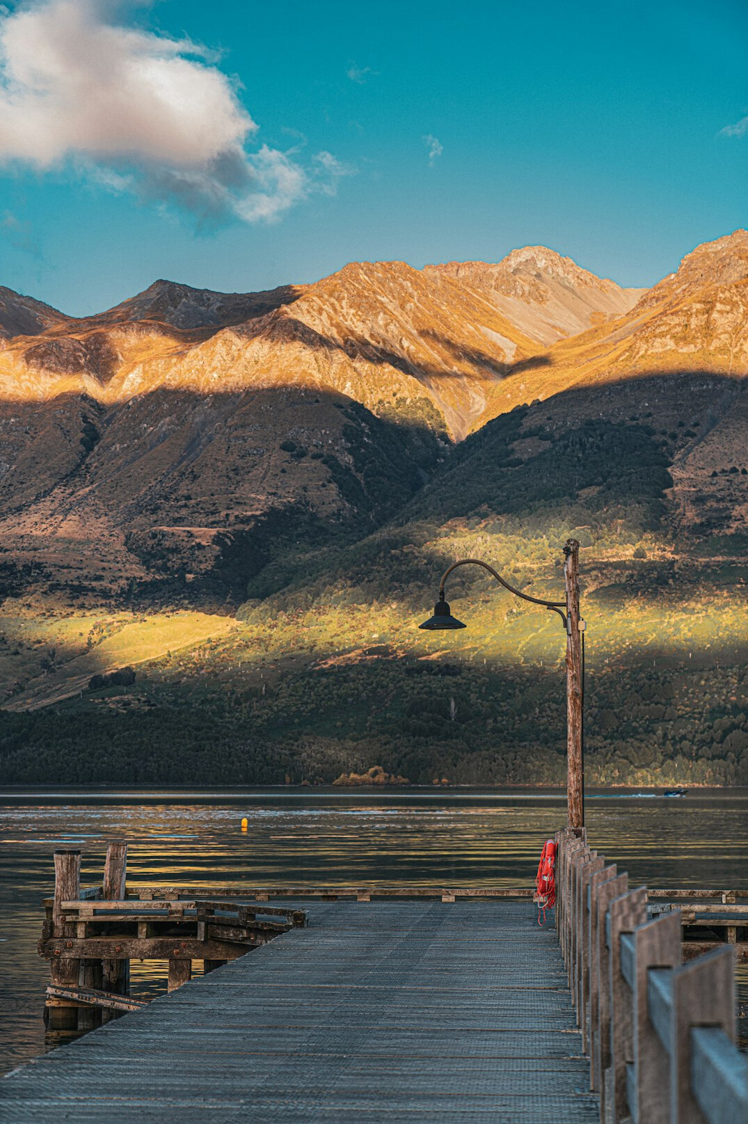 Wooden pier on a calm lake with mountains behind