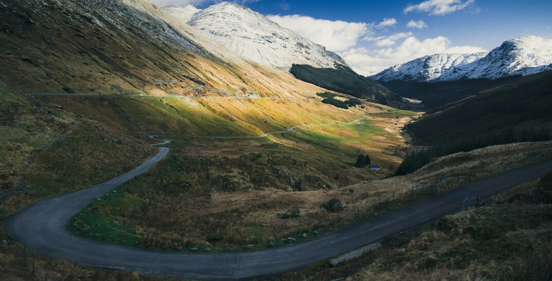 Road winding through a scenic valley with mountains